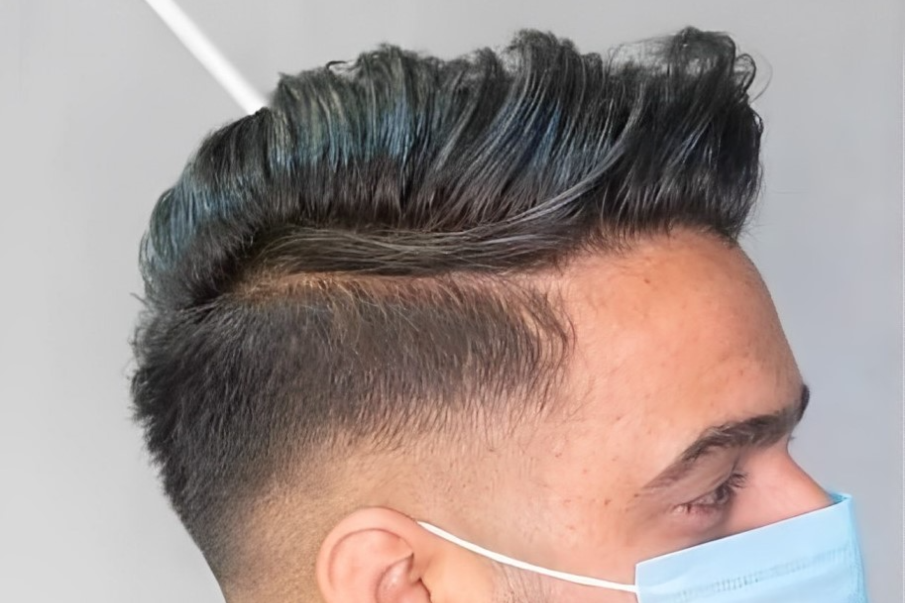 A man with a blue mask is rocking a side-swept haircut