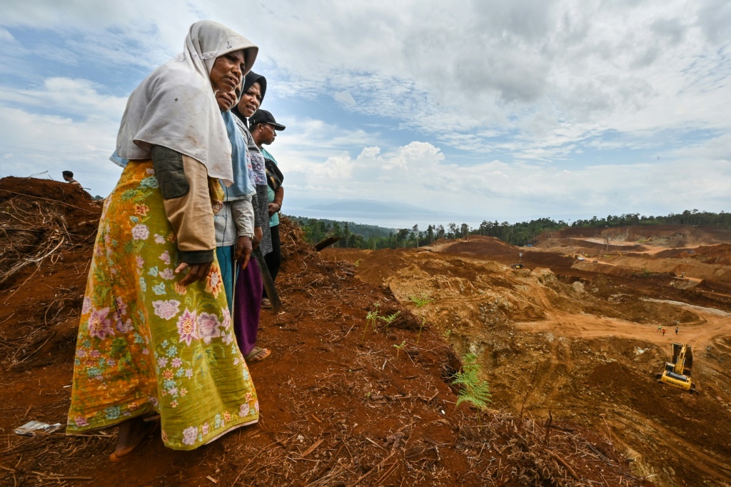 Royani (L) and others stand on their family land as they watch a nickel mining operation on Wawonii