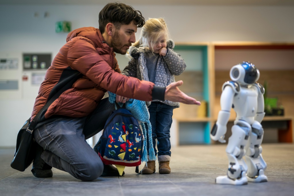 A father introduces his daughter to a robot called Nao in a Swiss creche