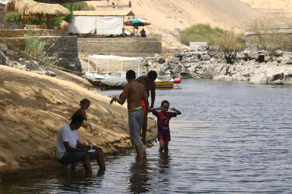 Sudanese who fled the war in their country cool off on the banks of the Nile river in the Egyptian city of Aswan