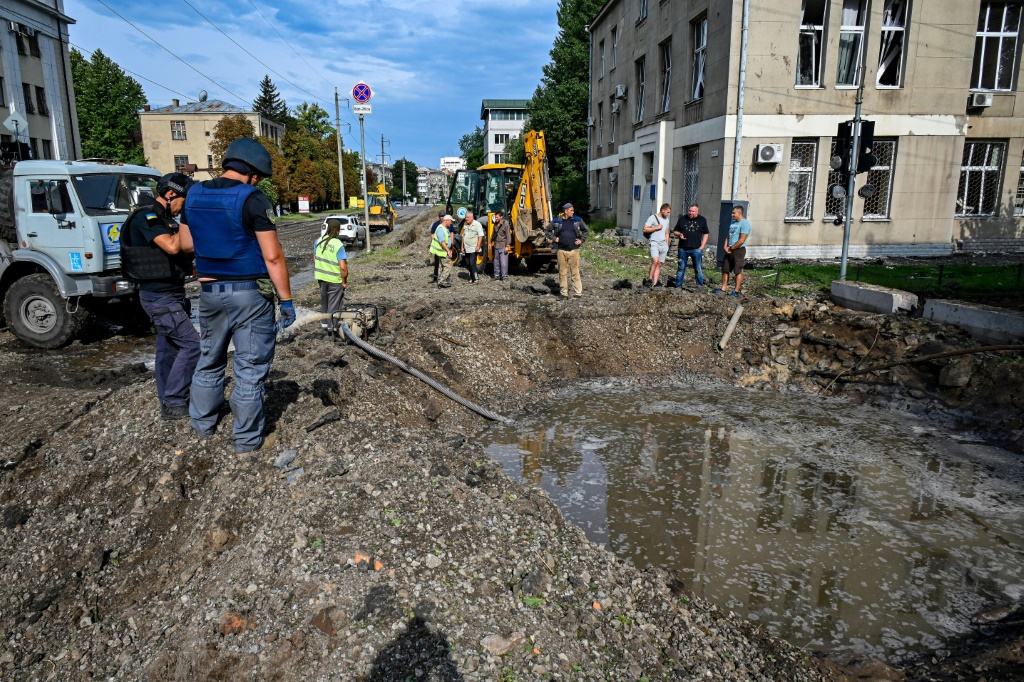 Municipal workers look at a crater left by an overnight strike in Kharkiv on Tuesday