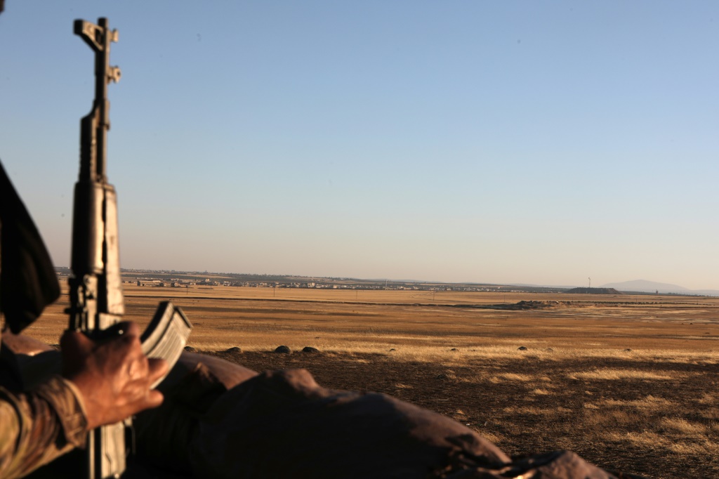 A Turkey-backed fighter in Syria looks towards the Kurdish-controlled area of Tal Rifaat