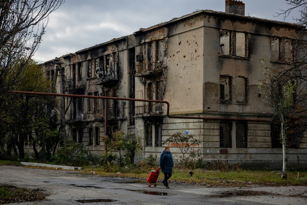 A woman walks past a damaged building in Lyman in the Donetsk region of Ukraine after the recapture of the area from Russian forces