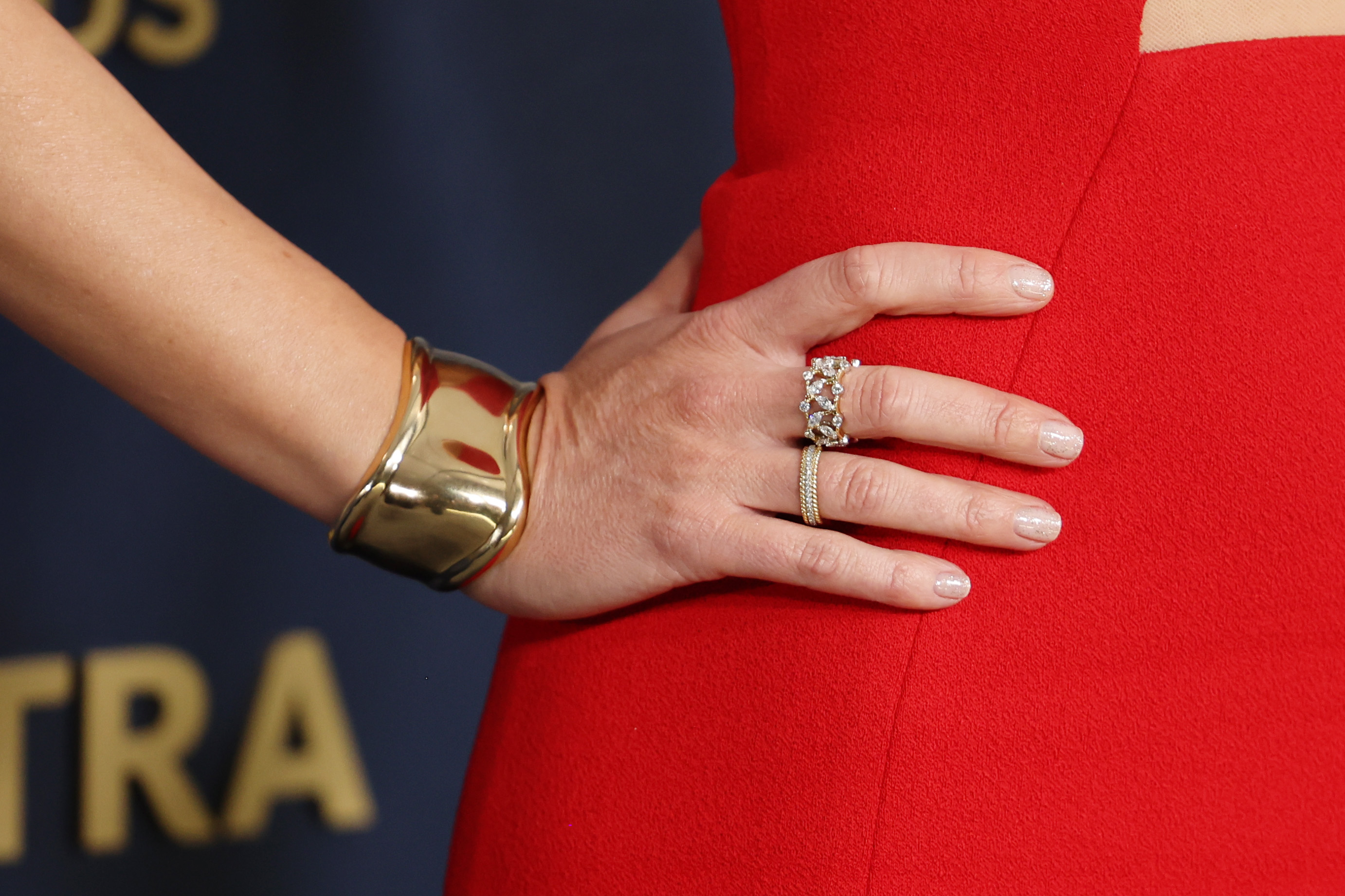 A woman in red wears a gold cuff around her wrist