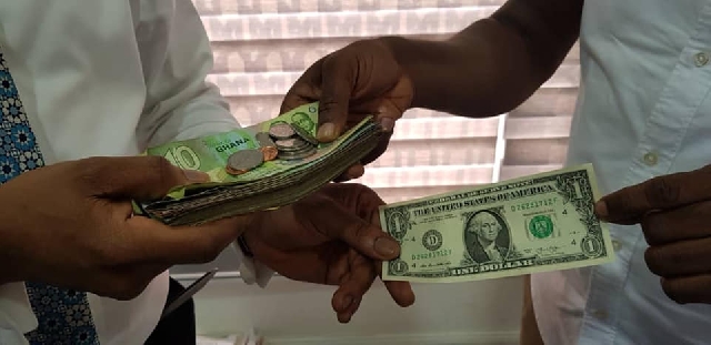 A stock image showing Ghana cedi notes and one US dollar.