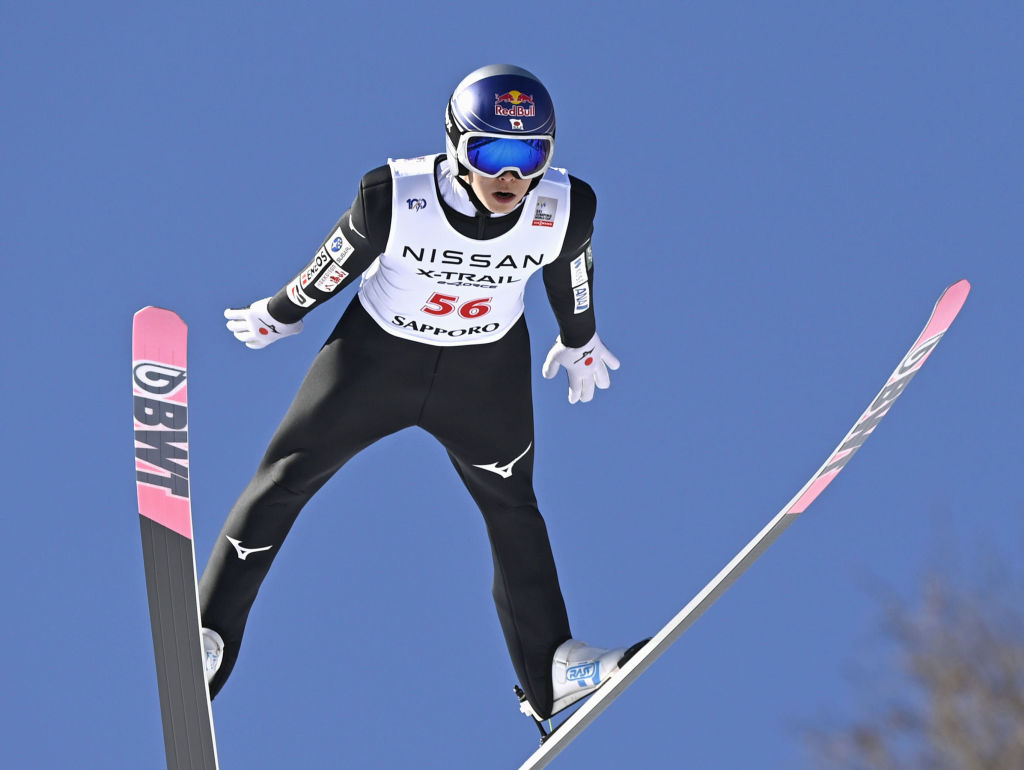 A ski jumper in mid-air, soaring through the sky with skis pointed downwards.