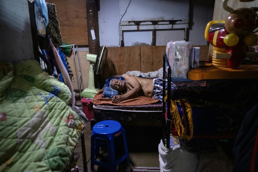 Arj Keawwilat, 88, is bedridden after recently having a fall trying to get to the bathroom. His daughter Orn has to juggle caring for him and running a small general store to support her household