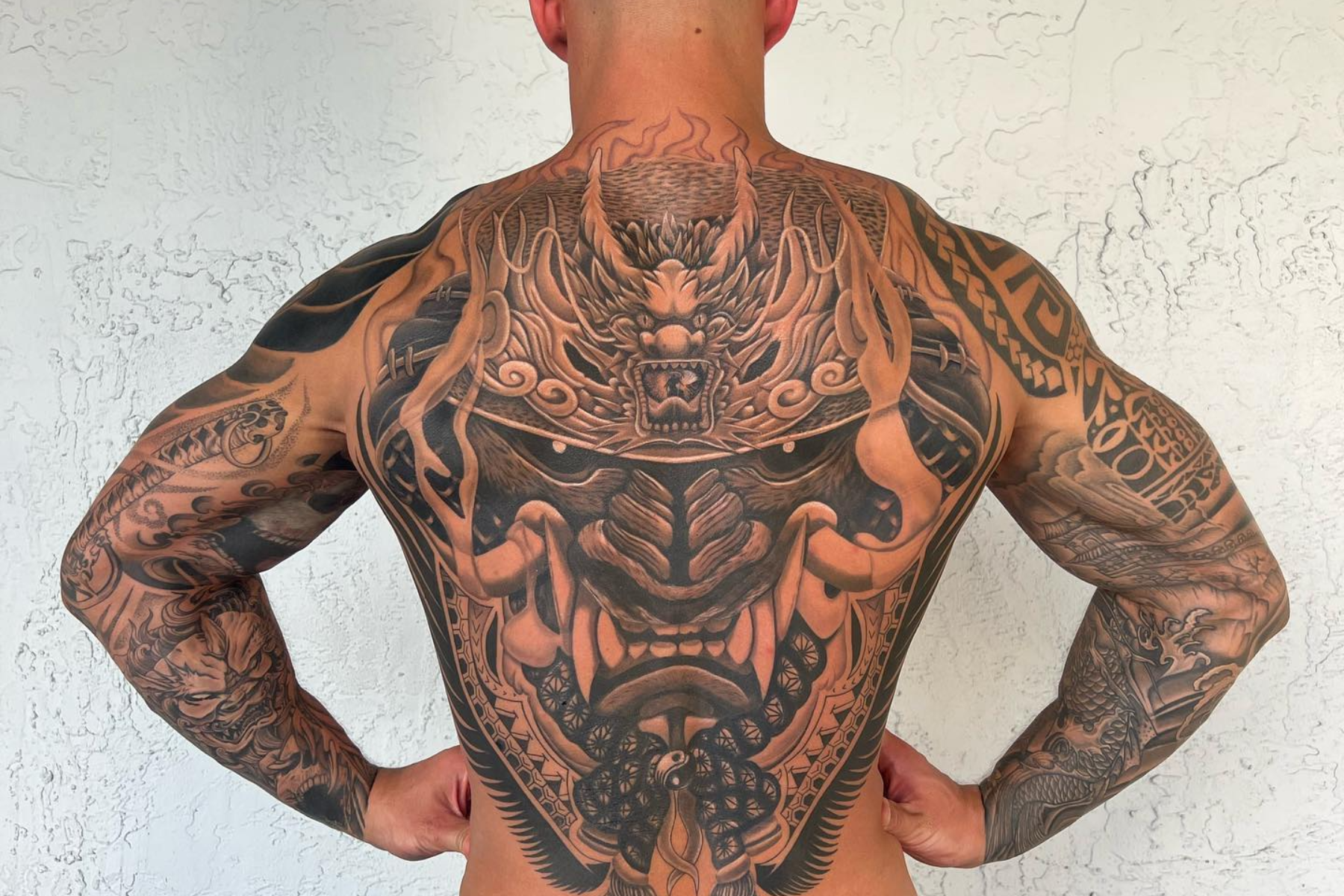 A man holding his waist has a full back tattoo