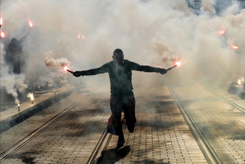 A protester holds burning flares during a demonstration in Nice