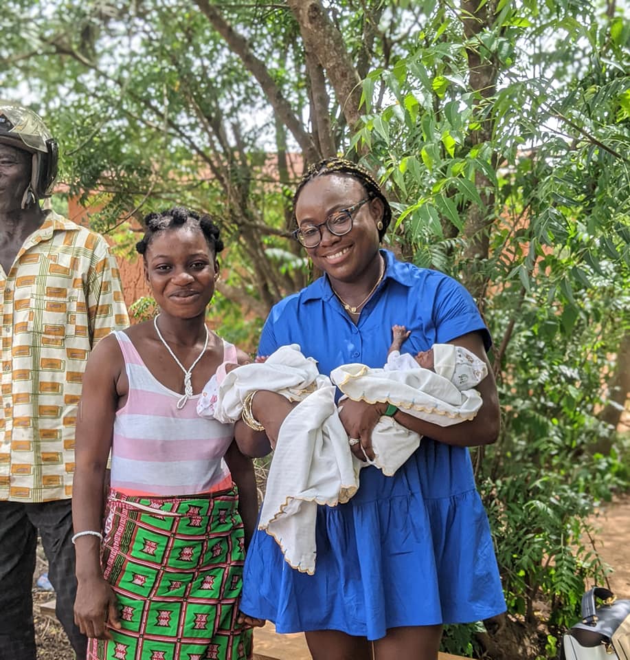 Mrs Poku holds preterm babies in her arms. Their mother stands next to her.