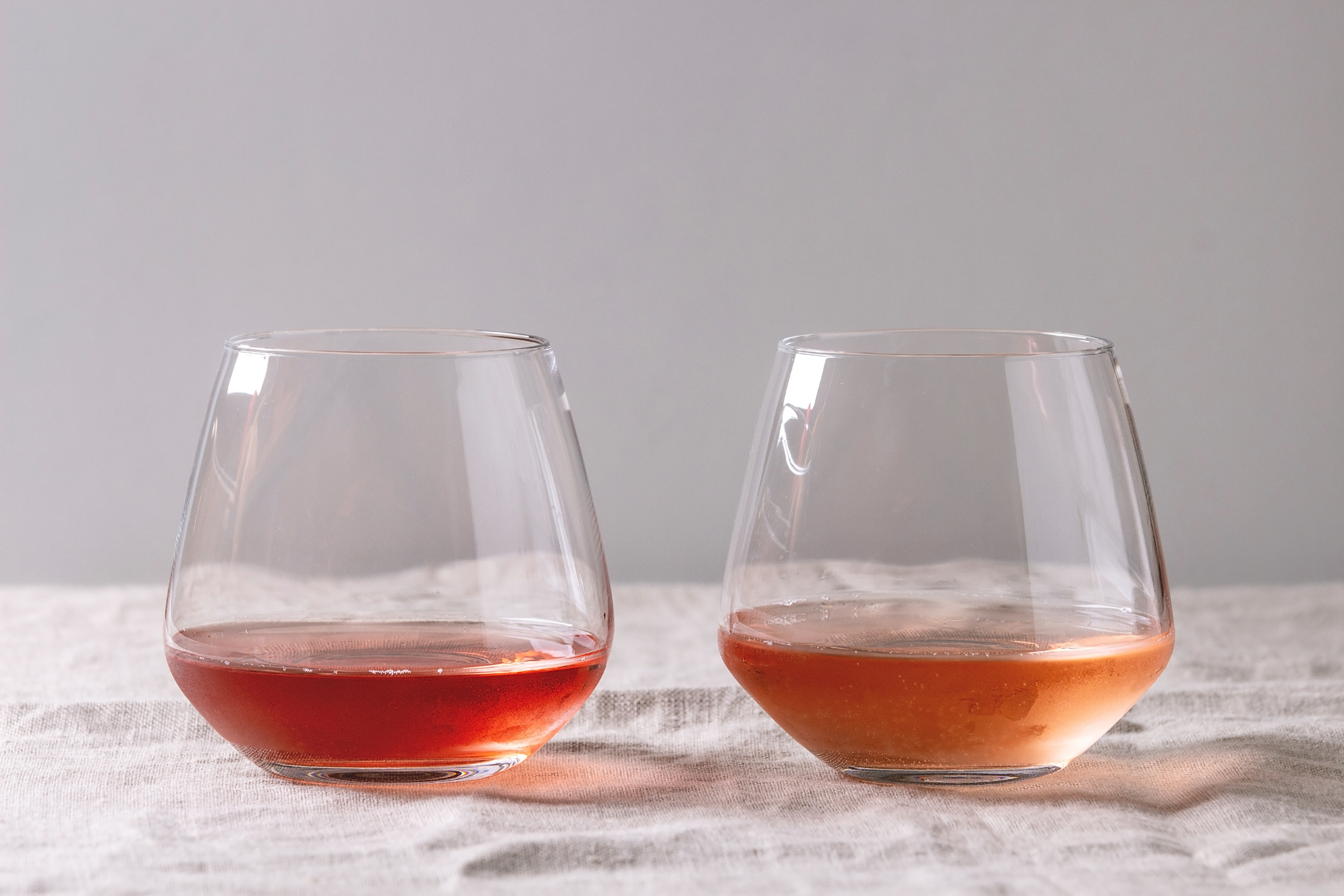 Different types of stemless wine glasses with rose wine.