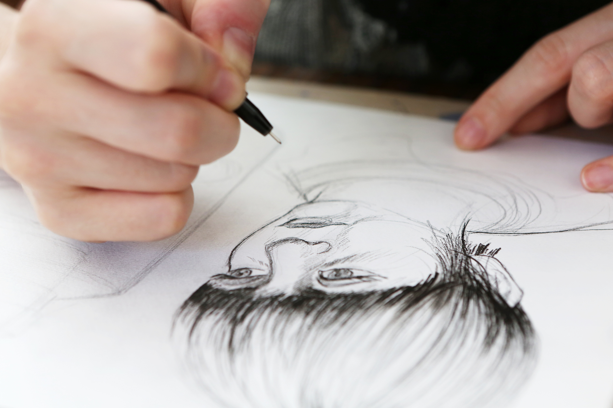 A person drawing someone on a paper