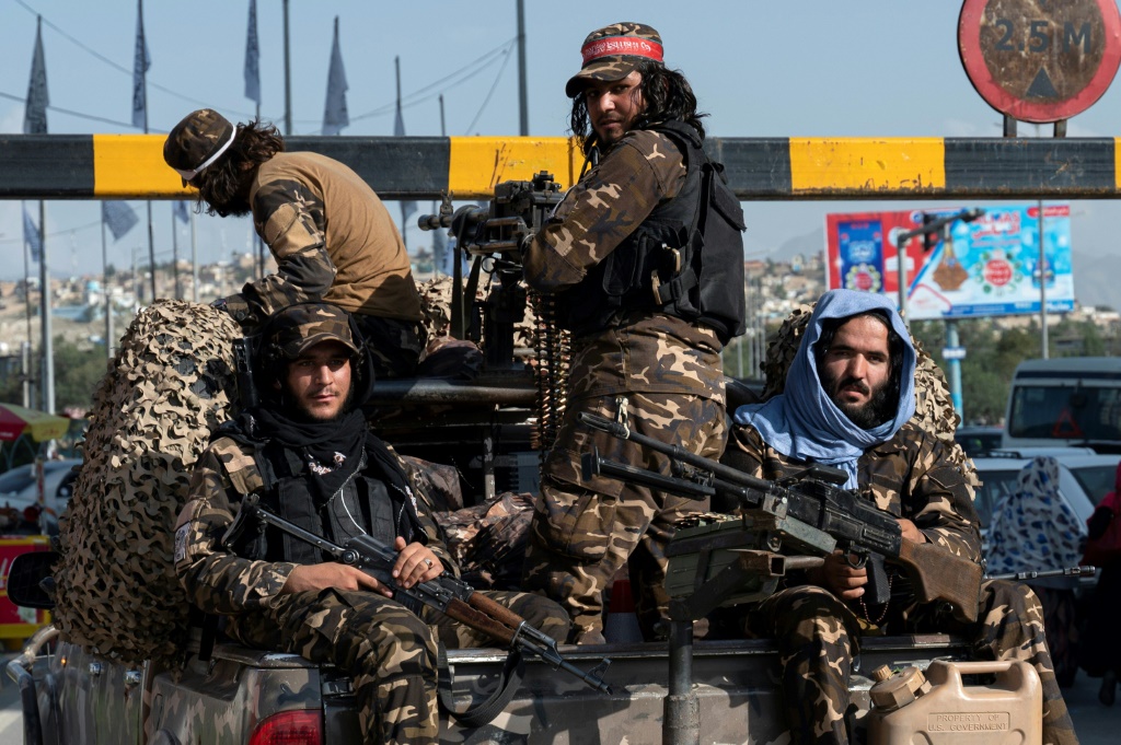 Taliban fighters travel along a road at the back of a pickup vehicle in Kabul