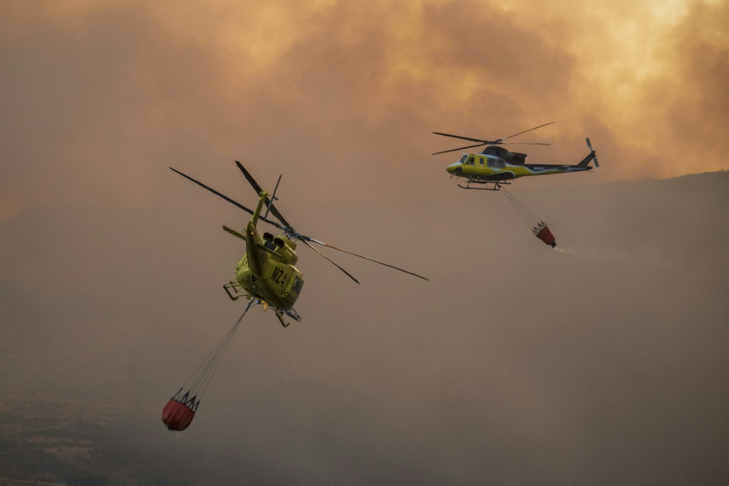 Two firefighter helicopters fly over blaze in a national park in northwestern Spain in late August, amid blistering summer heat. In October, Spain recorded the hottest temperatures for that month since records started in 1961
