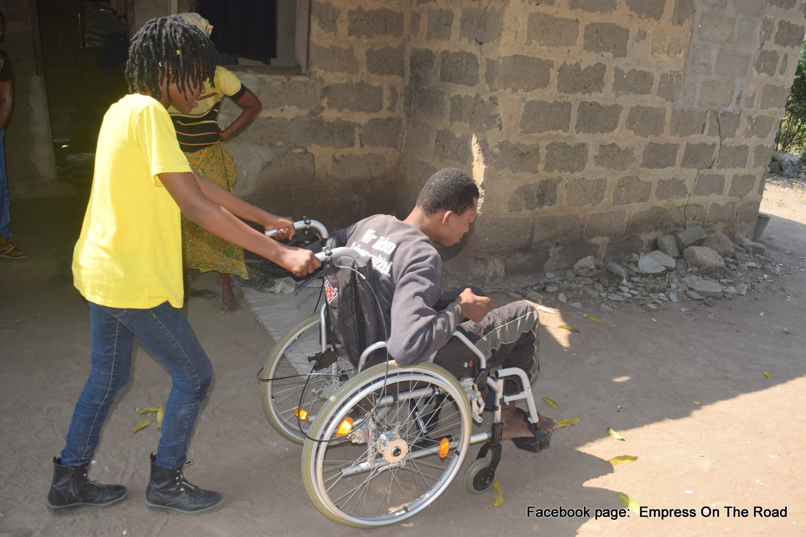 Photo of Empress Esi helping a man living with a disability.