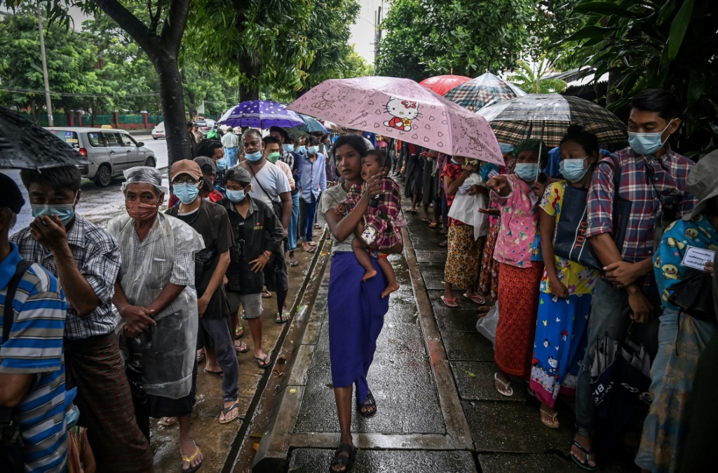 People line up for a free meal along a street in Yangon