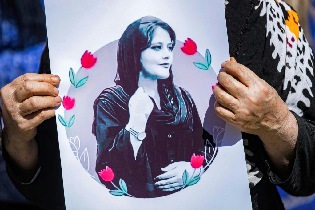A woman holds up a picture of 22-year-old Mahsa Amini during a solidarity demonstration in Syria's northeastern city of Hasakeh on September 25, 2022