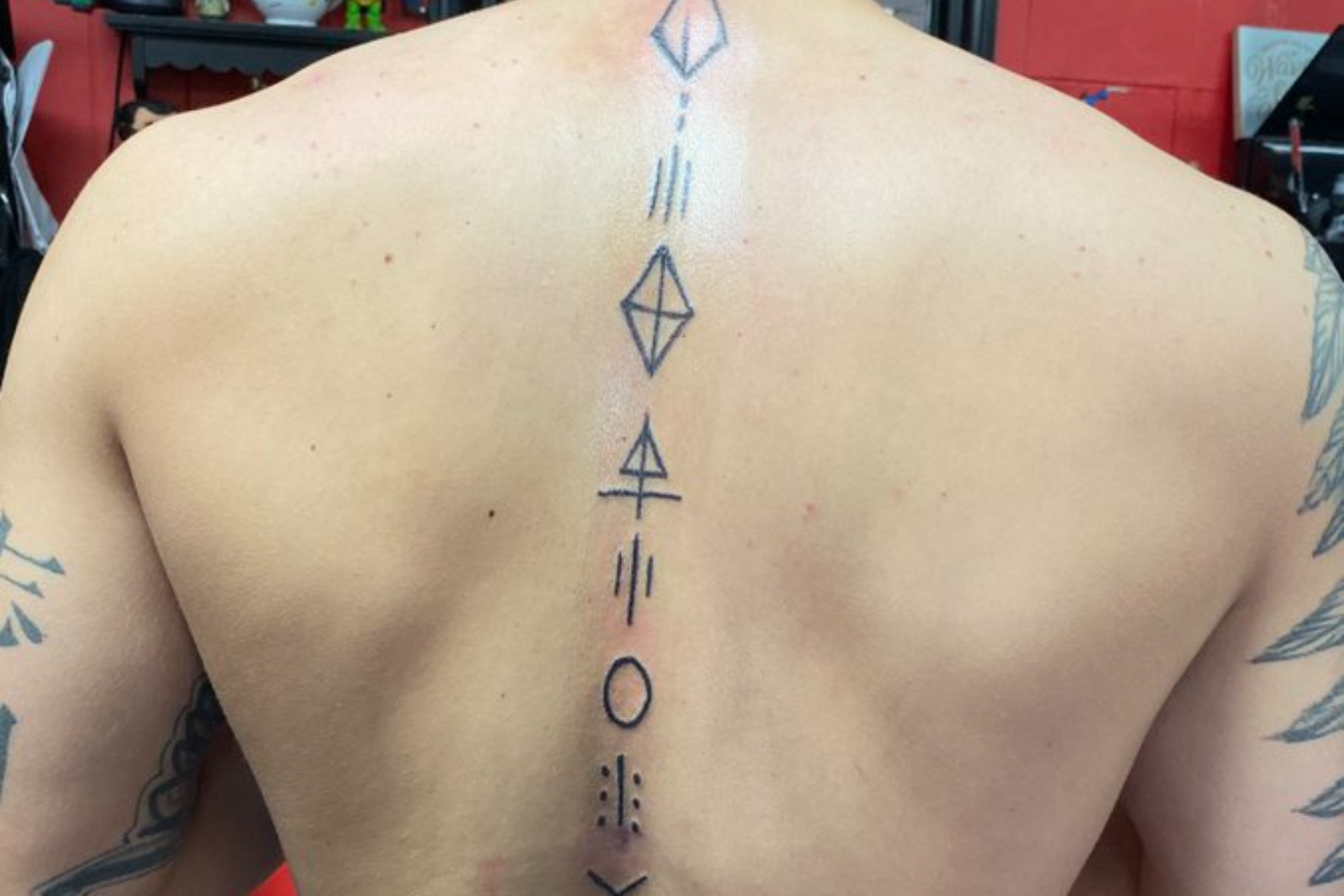 A man has a vertical tattoo along his spine