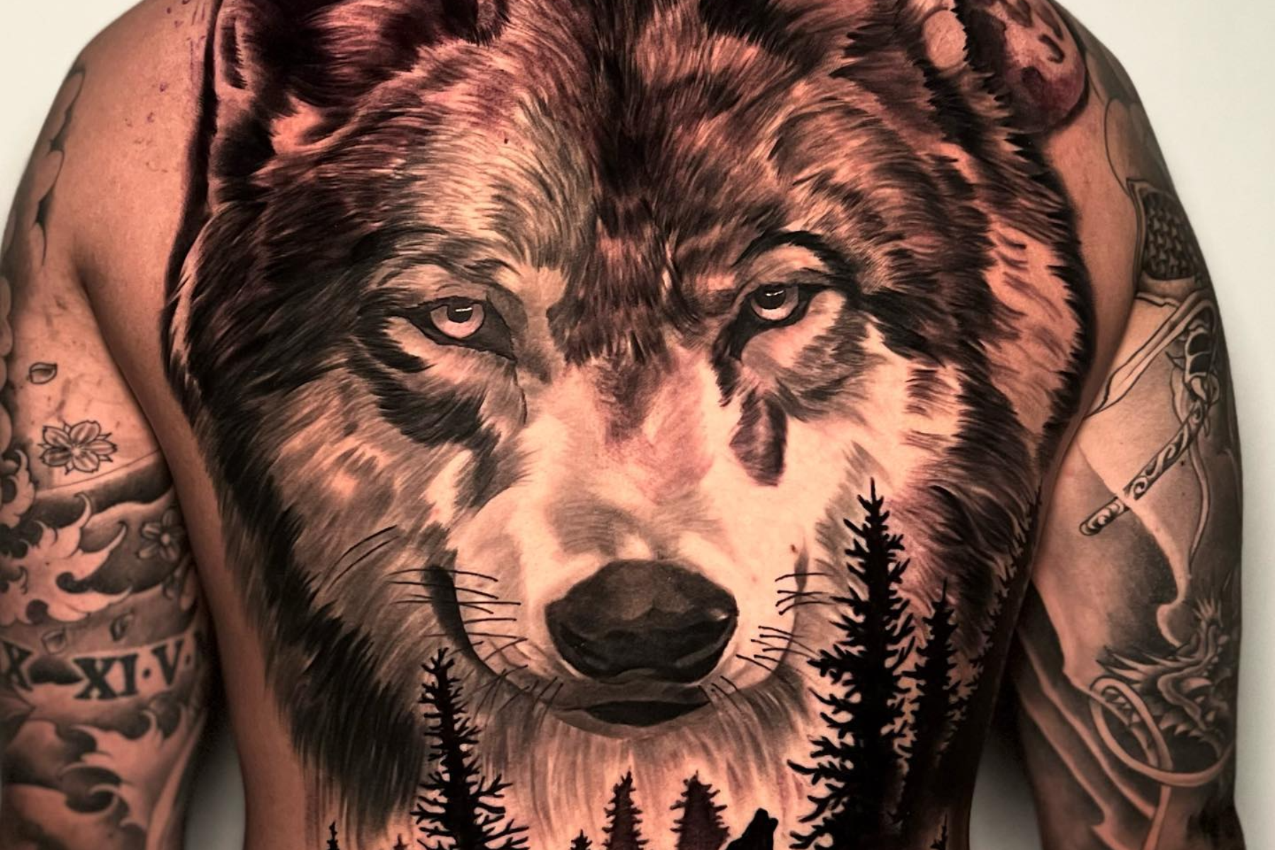 A man is donning a wolf head tattoo on his back