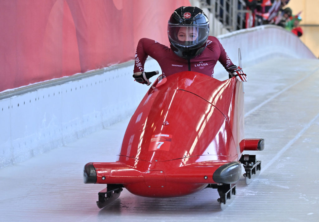 A person joyfully sleds down a track on a red sled.