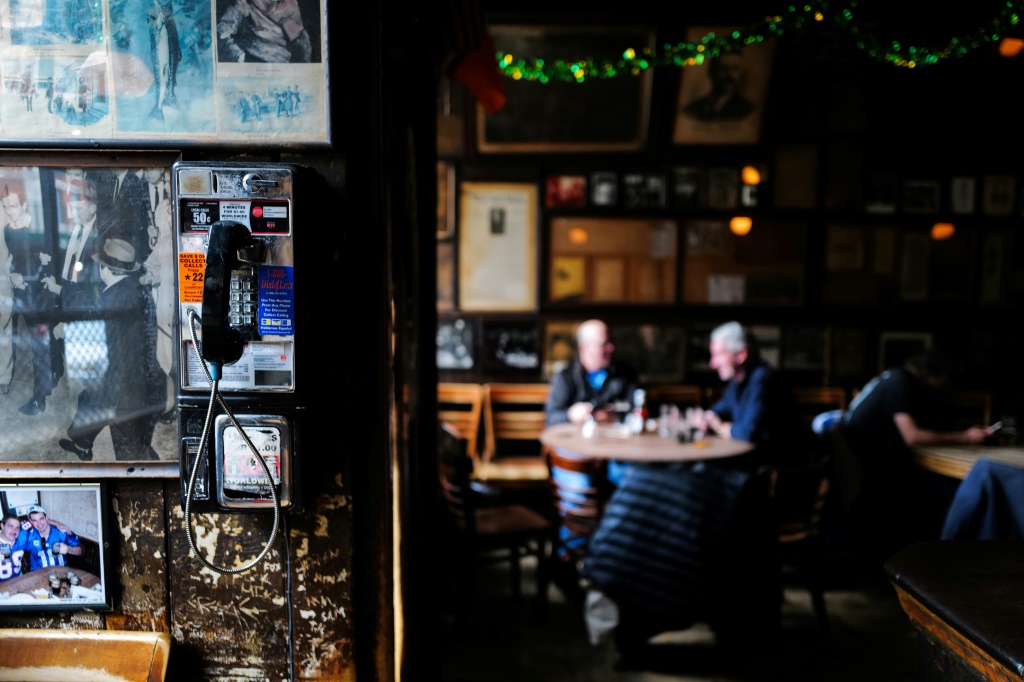 A long out-of-vogue public phone is seen on the wall as customers drink beers at McSorley's Old Ale House in New York on February 18, 2024