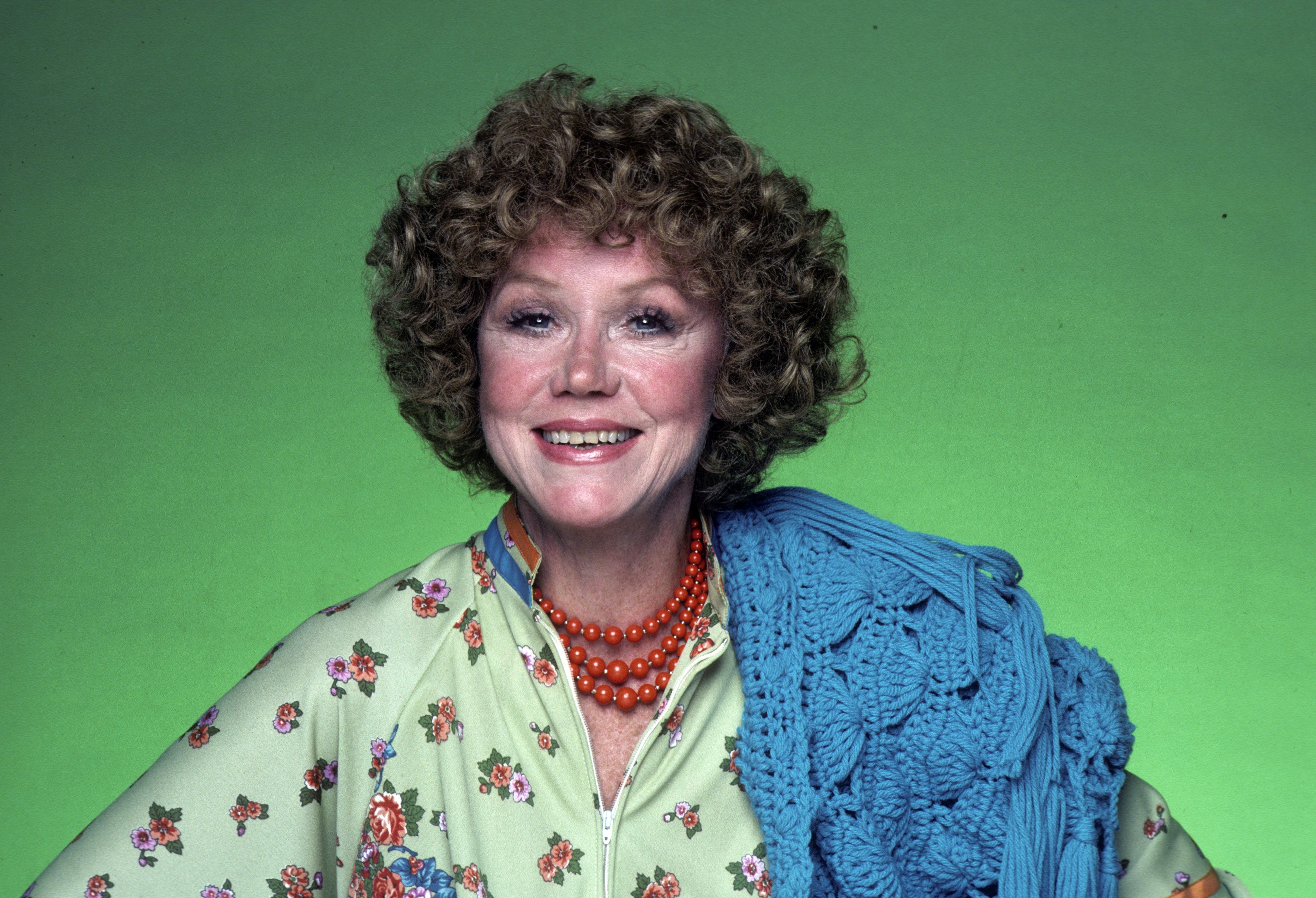 Audra Lindley stands next to a green background