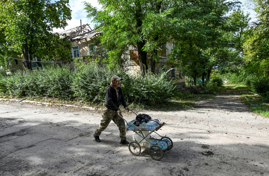 Sergiy Medvedev pushes water containers through the streets of Siversk in Ukraine's Donetsk region