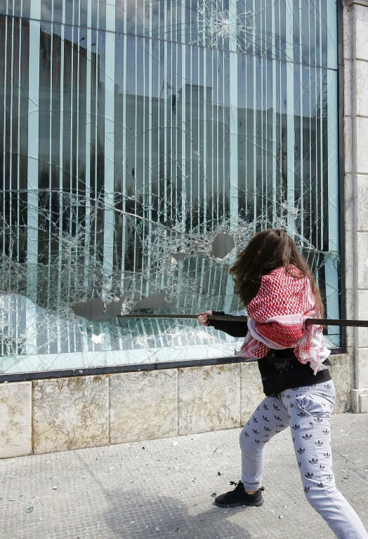A Lebanese protester smashes the facade of a bank at Al-Nour square in Lebanon's northern port city of Tripoli, on April 28, 2020
