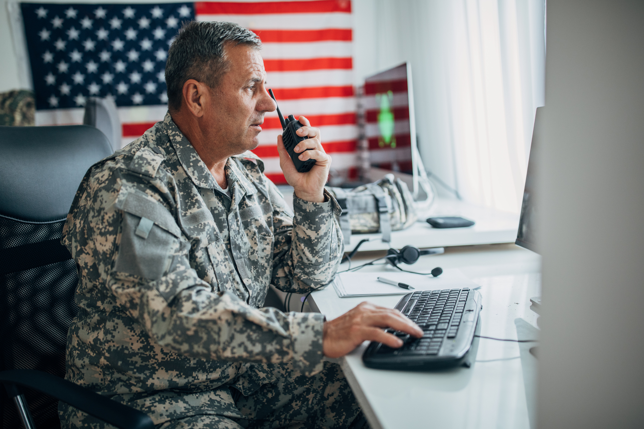 A military man talking on a walkie-talkie