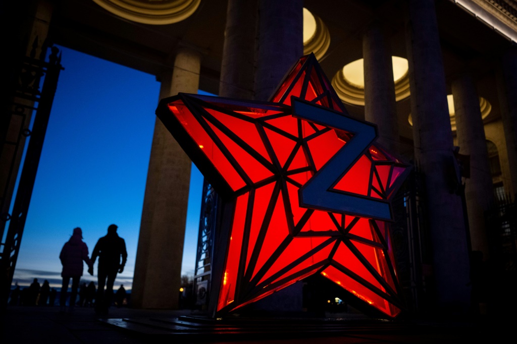 Pedestrians walk past a New Year decoration stylised as the 'Kremlin Star,' bearing a Z letter, a tactical insignia of Russian troops in Ukraine