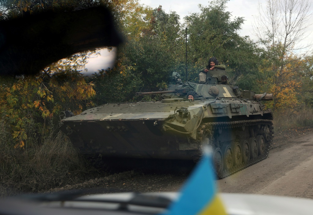 Ukrainian soldiers ride an armoured personnel carrier down a road in the Donetsk region