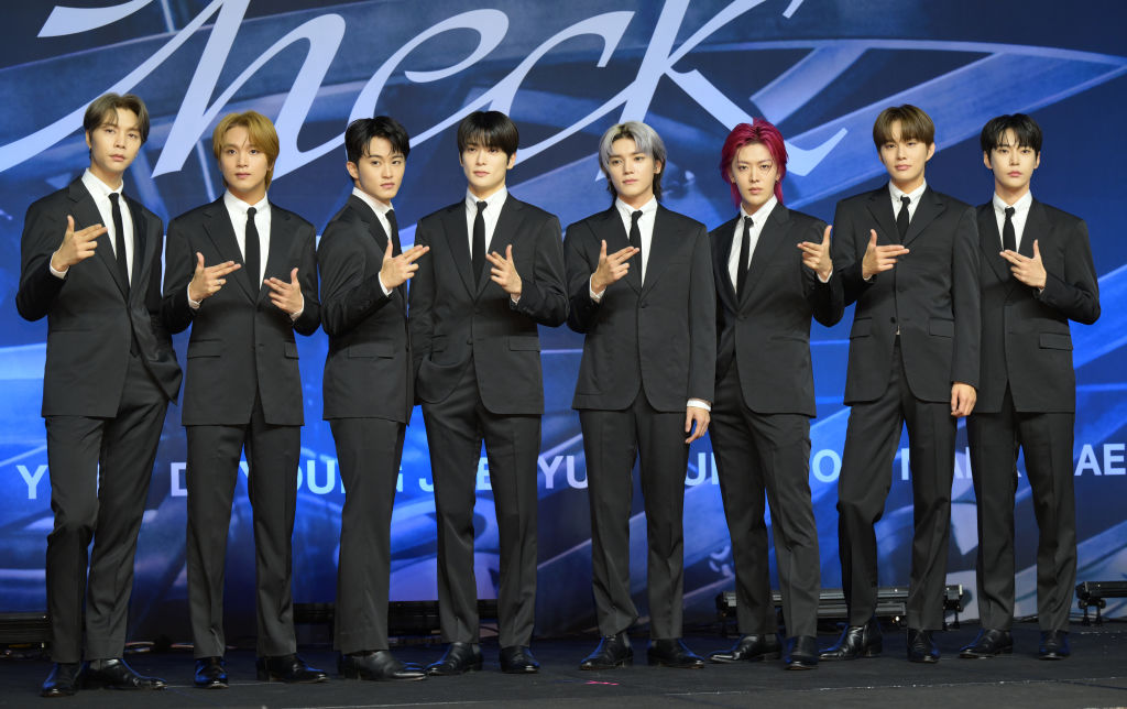 K-pop boy group, NCT 127, are posing for a photo in black suits.