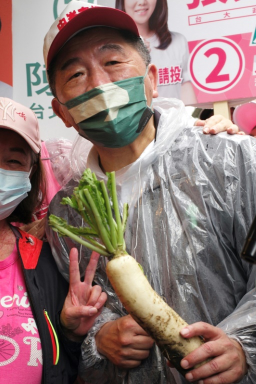 Taipei mayoral candidate Chen Shih-chung of the ruling Democratic Progressive Party poses with a radish on the campaign trail