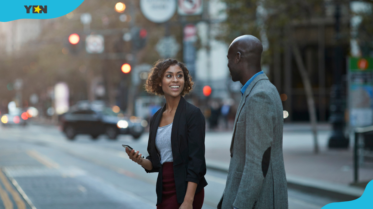 A happy young lady and man talking while crossing a road
