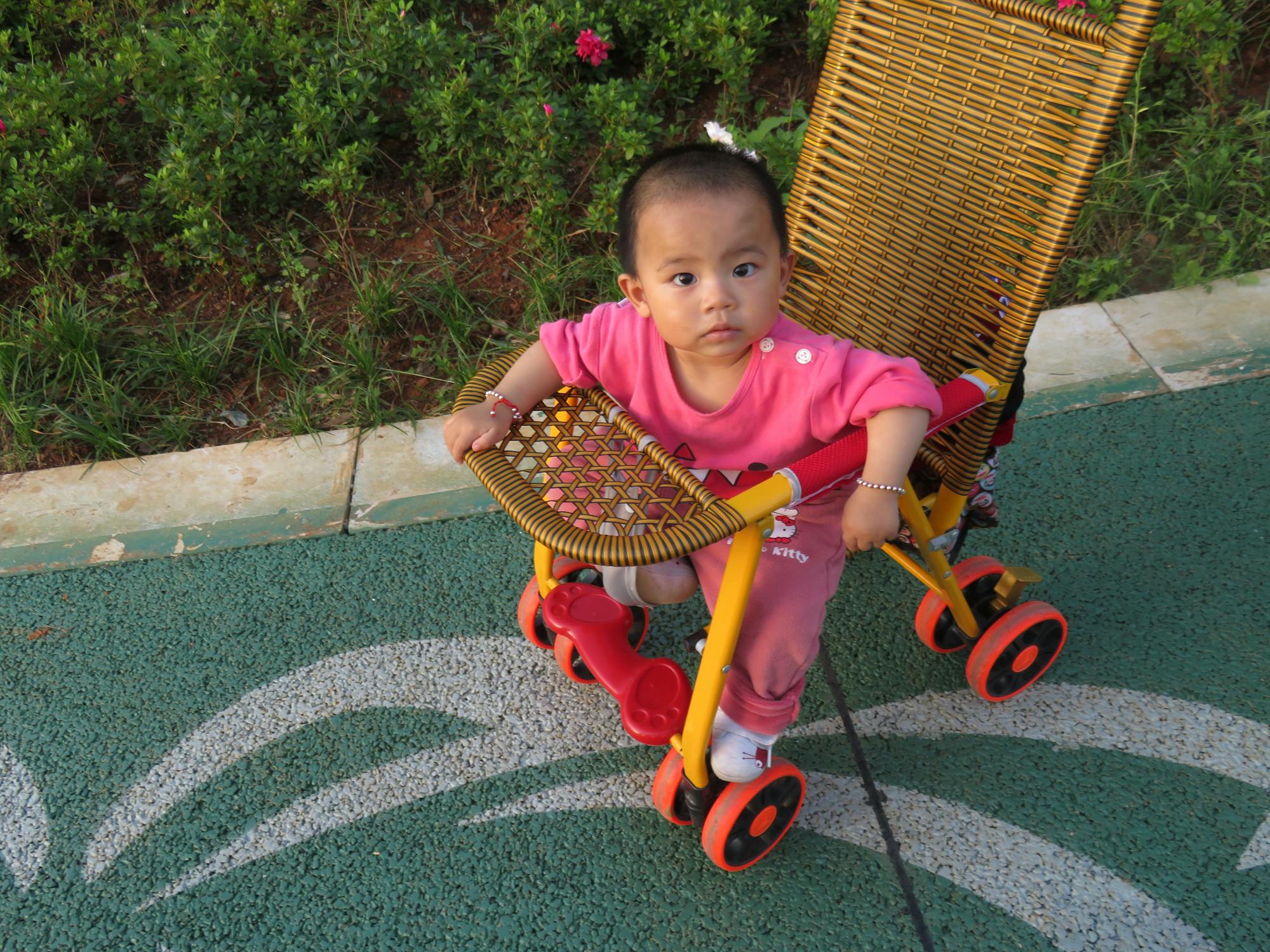A cute baby girl sitting on a woven stroller