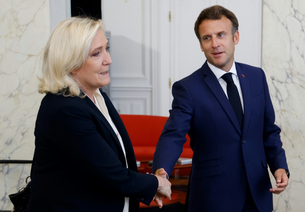 Marine Le Pen's far-right National Rally is the largest opposition party in parliament. President Emmanuel Macron (r) is struggling to put together a majority