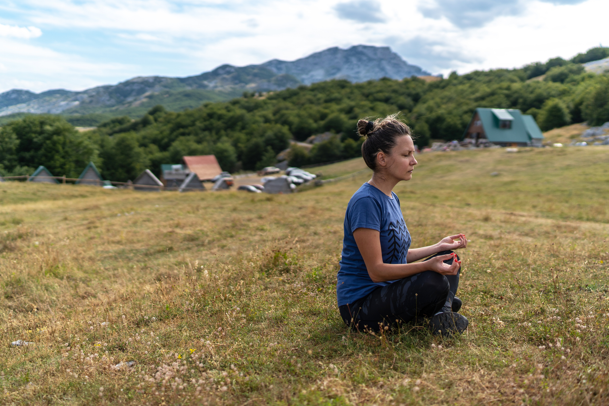 A young woman meditates in the mountains.