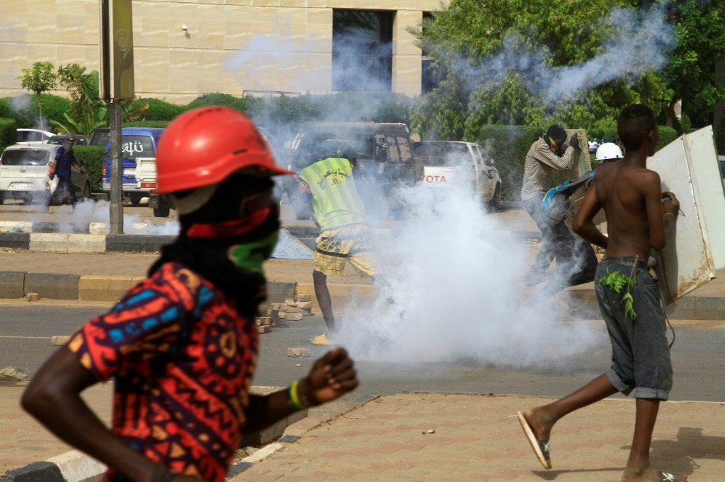 Youths run from tear gas fired by security forces as they protest in south Khartoum on August 31, 2022, to demand the return of civilian rule