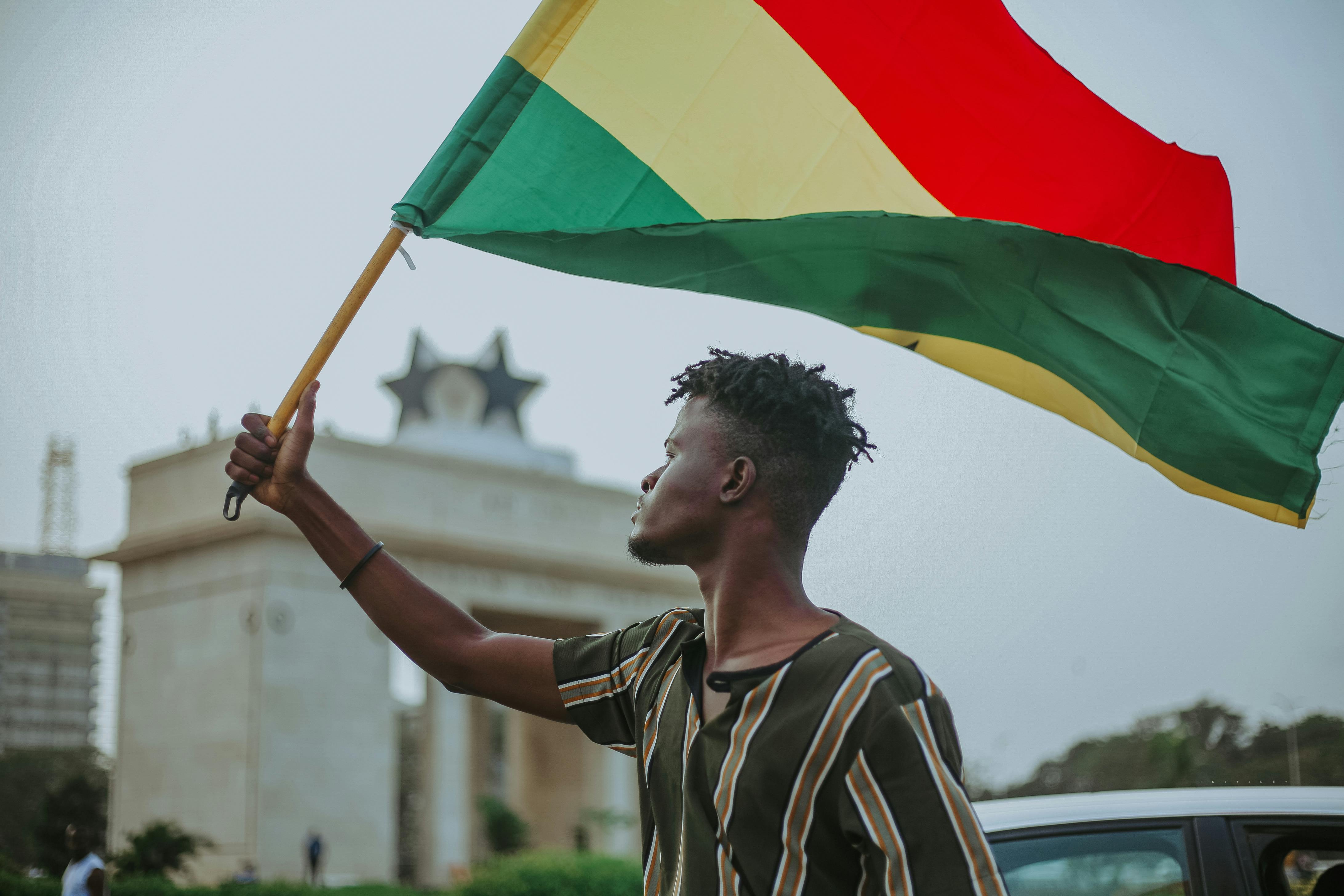 A young man holding the Ghanaian flag at the Black Star Gate