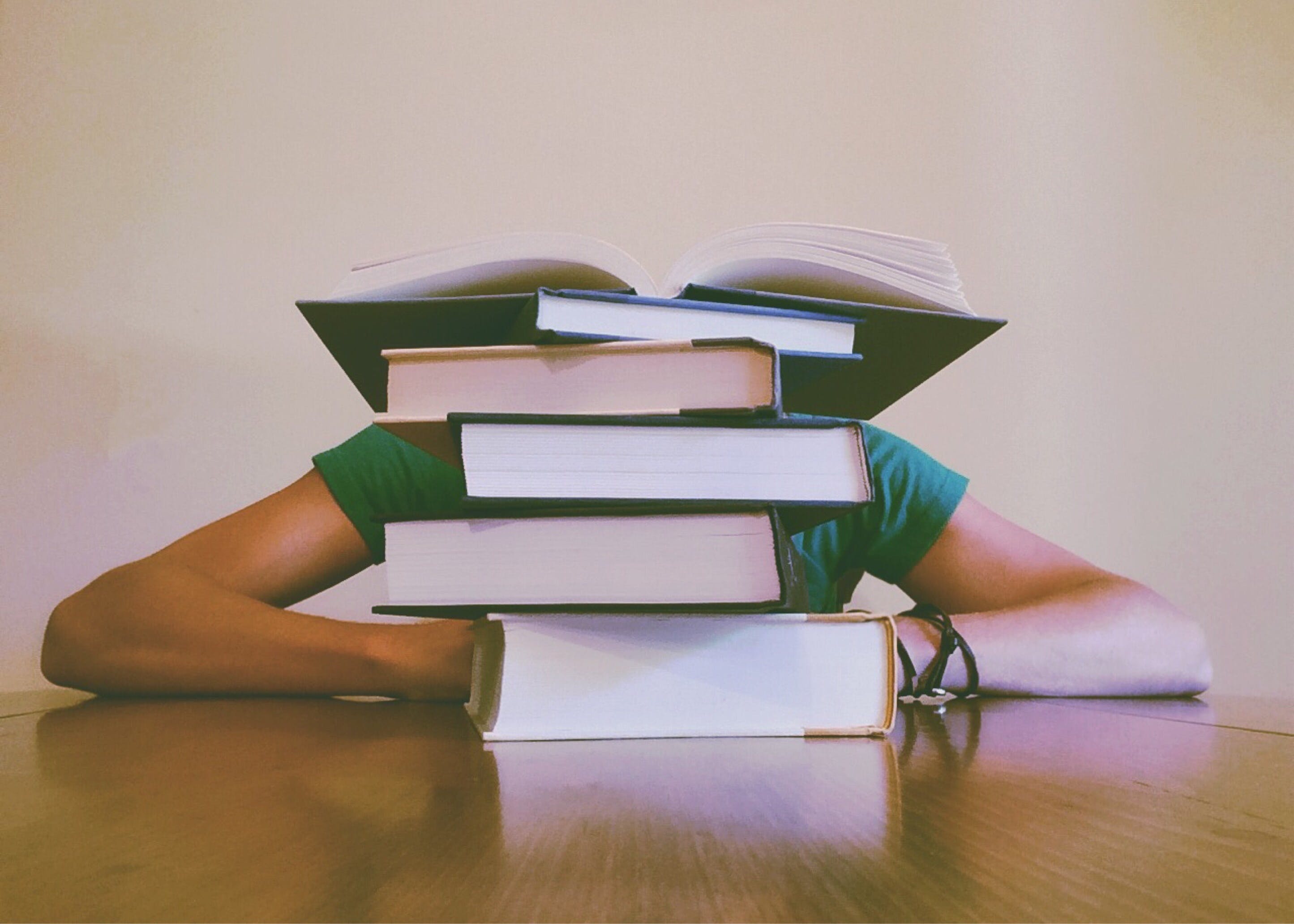 A student lying a desk with a heap of book
