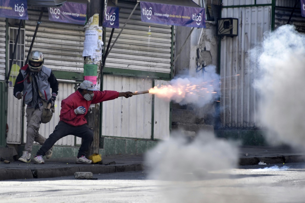 A Bolivian protester throws firecrackers at police officers during a protest march by coca leaf growers in La Paz, on August 2, 2022