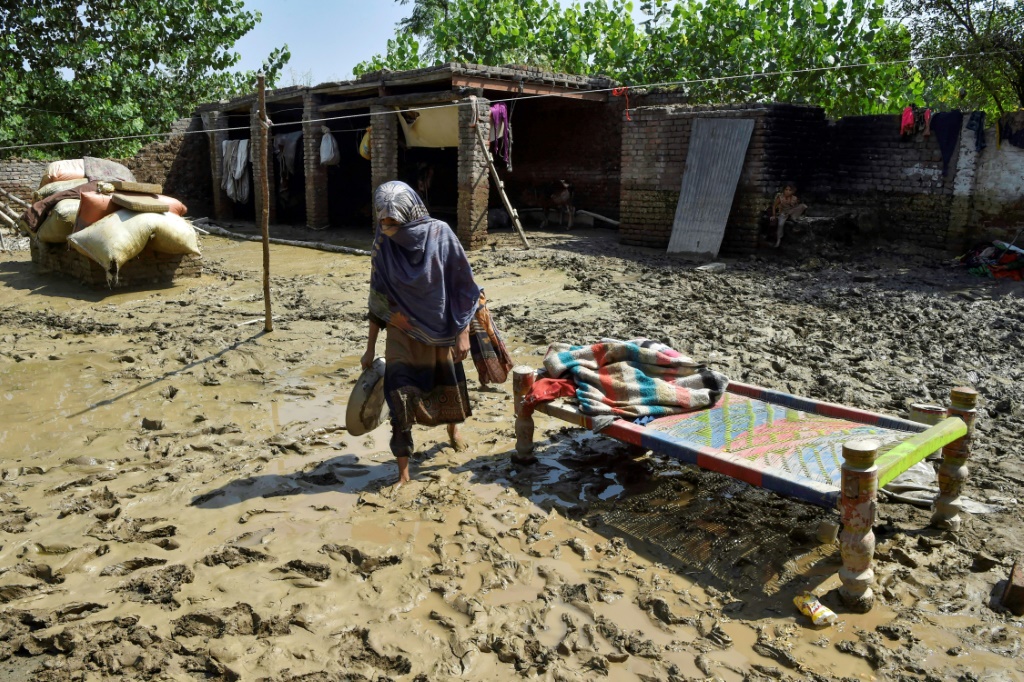 A woman walks plods through the mud outside her flood-damaged home in Jindi village, Khyber Pakhtunkhwa