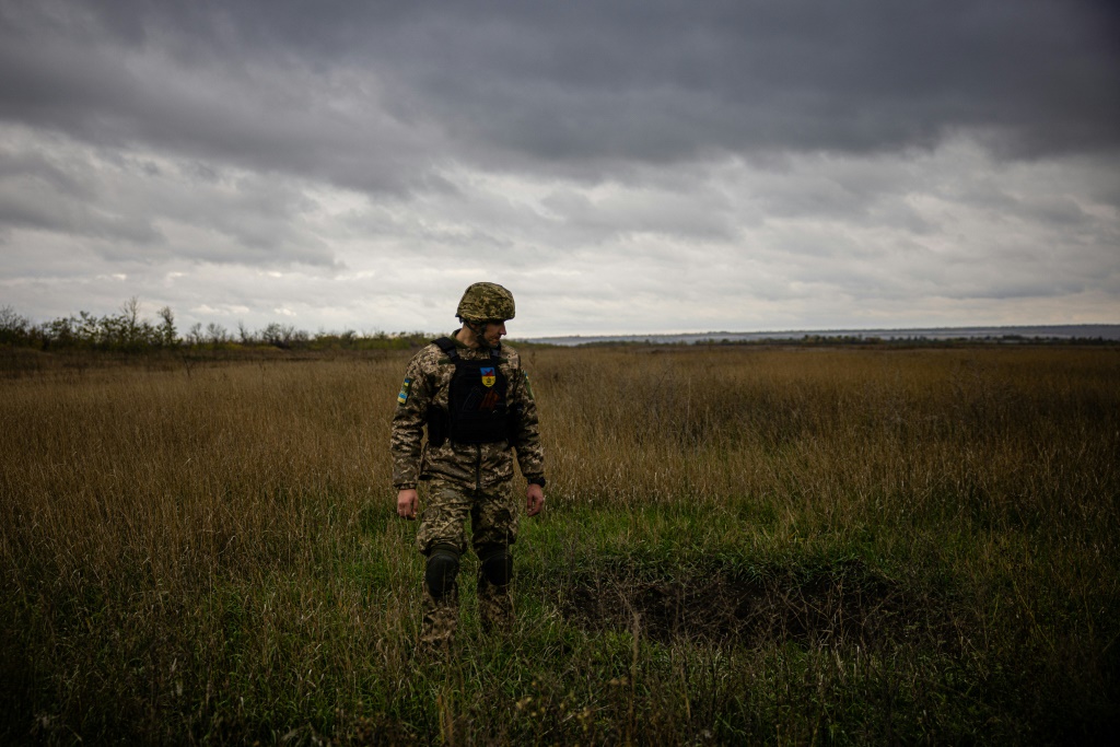 A Ukrainian serviceman stands next to a mortar crater in a field in the Donetsk region of eastern Ukraine