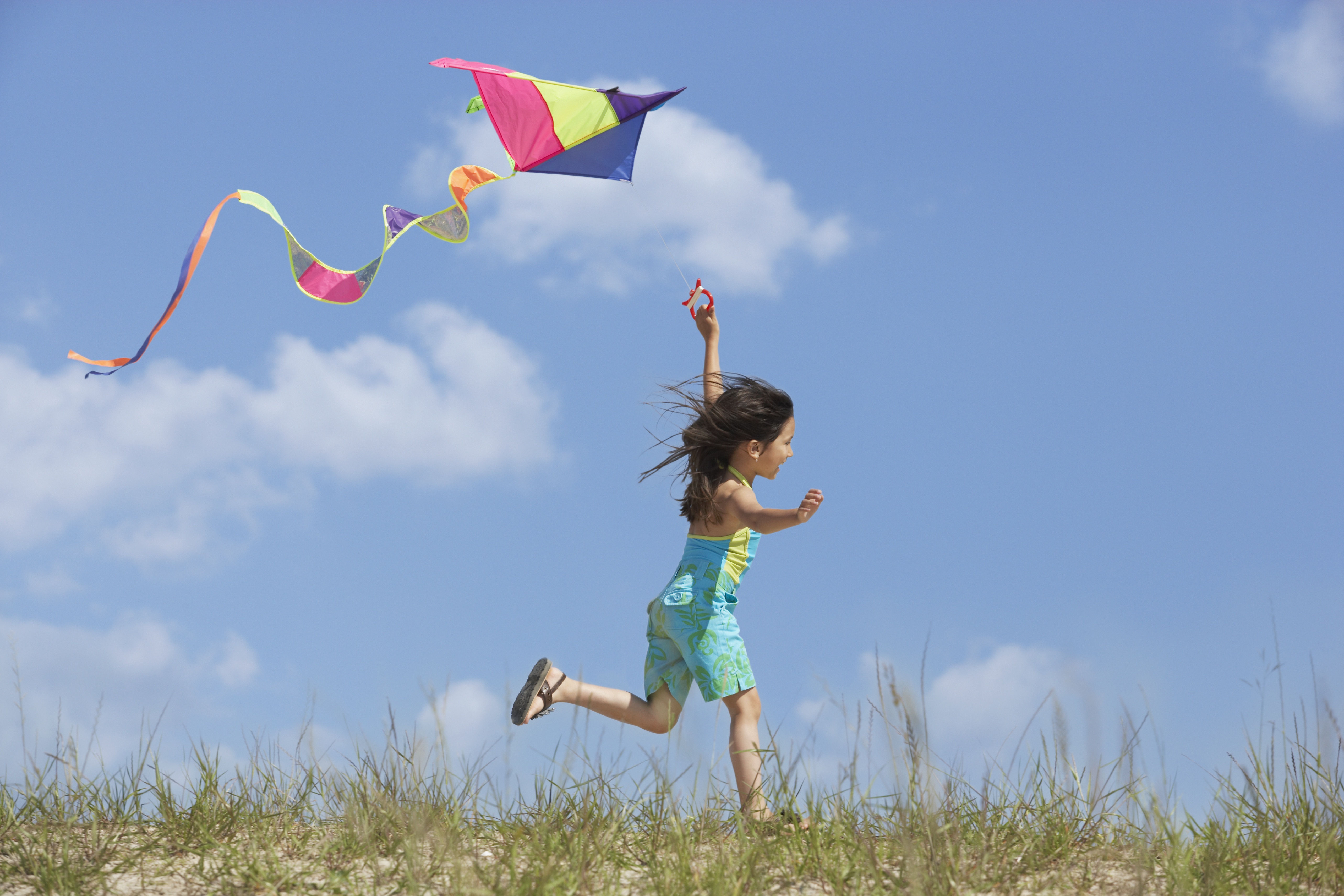 A Hispanic girl is flying a kite
