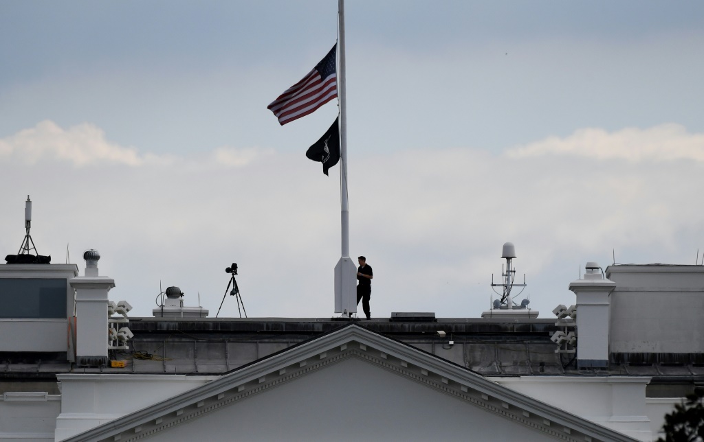A man lowers the US flag above the White House to half-staff following the death of Queen Elizabeth II