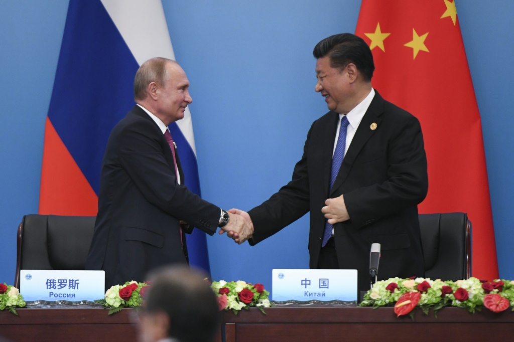 Chinese President Xi Jinping (R) shakes hands with Russian President Vladimir Putin in 2018 -- they are seeking to further deepen the "no-limits" partnership between their two countries