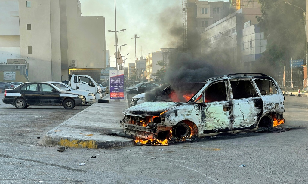 Damaged vehicles are pictured on a street in the Libyan capital Tripoli on August 27, 2022, following clashes between rival Libyan groups
