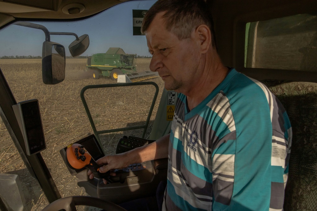 A worker drives a combine harvester collecting sunflower seeds near Kryvyi Rig