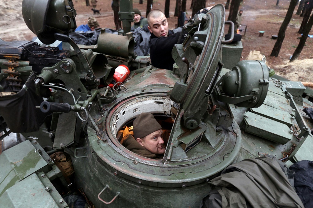 Ukrainian servicemen repair a captured Russian tank in a forest near the front line in the Kharkiv region