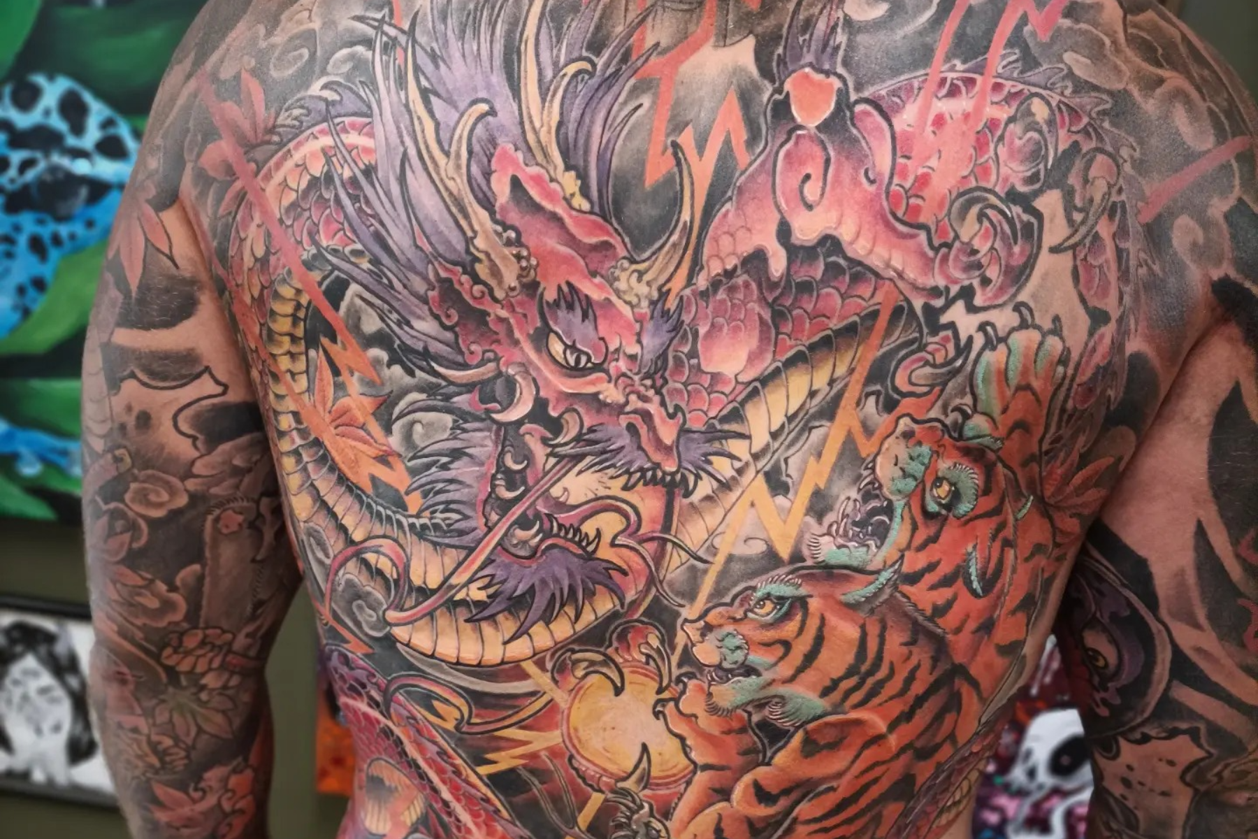 A man has an intricate dragon tattoo on his back